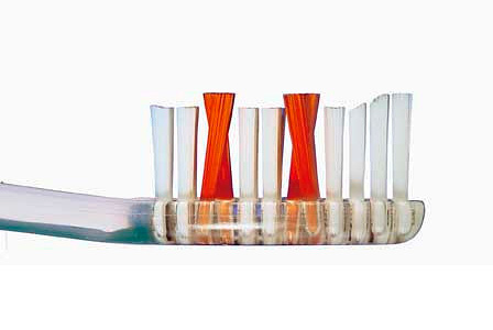 Fotografie ukazuje příklad zubního kartáčku s chomáčky štětin různých délek a jejich uspořádání ve tvaru X