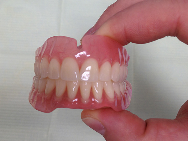Fotografia prezintă o proteză acrilică detașabilă completă pe maxilarul superior și inferior.